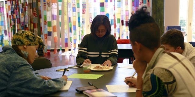 A student works on a poem at a table. 