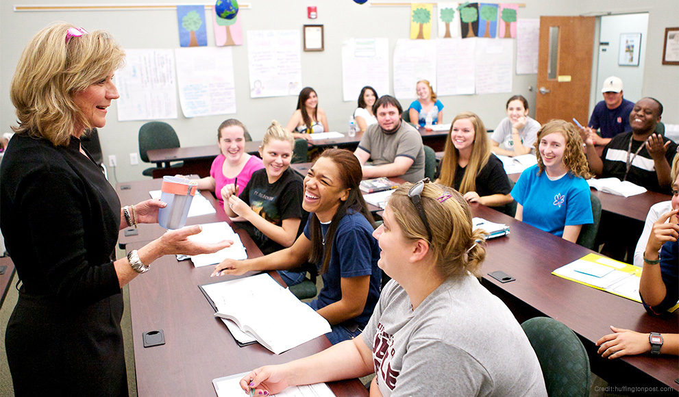 High school students engage with a teacher in a classroom. 