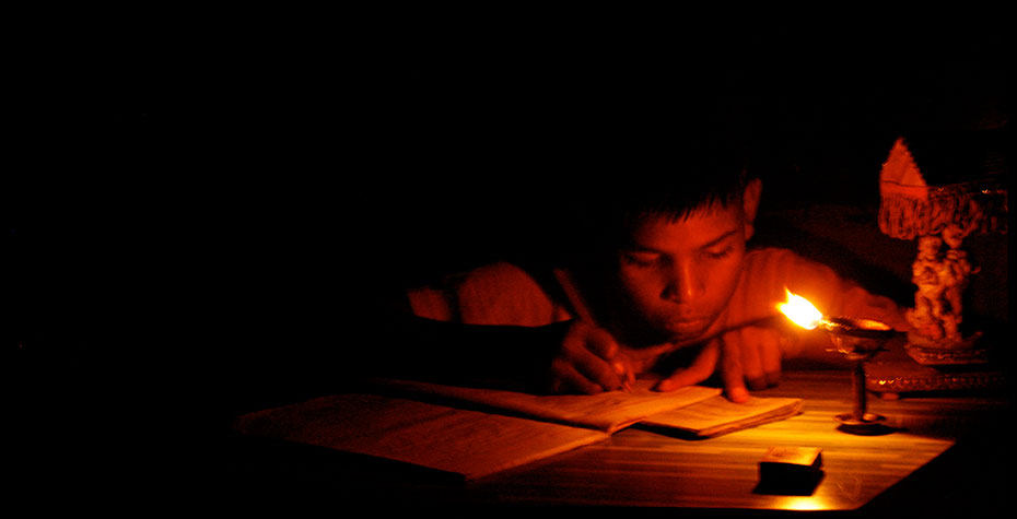 young student studies by candlelight in dark