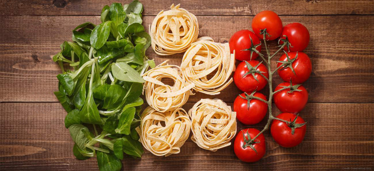 Basil leaves, pasta and tomatoes arranged to represent the Italian flag. 