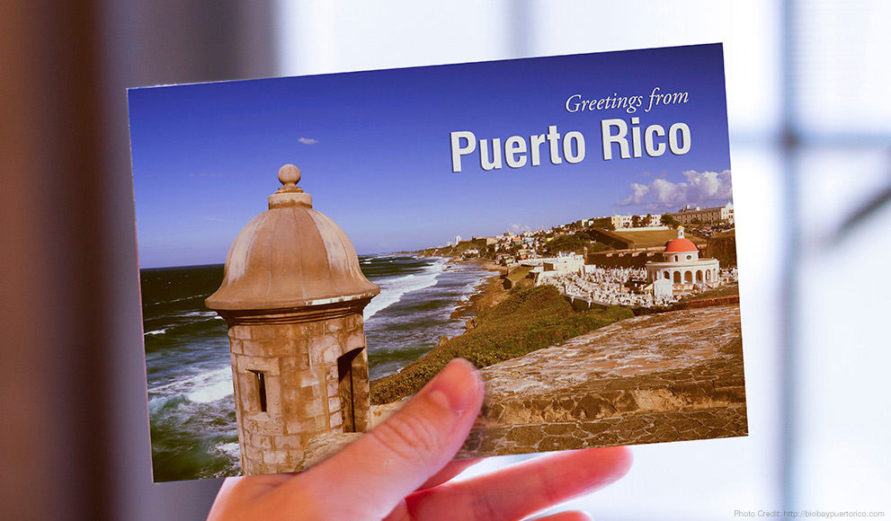 Hand holds a postcard that reads "Greetings from Puerto Rico"