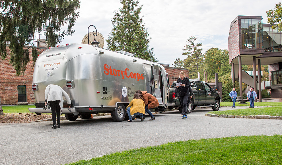 A silver airstream trailer, the StoryCorps MobileBooth, parked near the Wellelsey student center