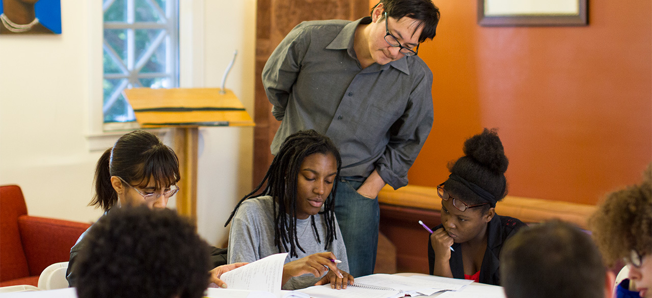 Professor Stanley Chang looks on as a group of students study together. 