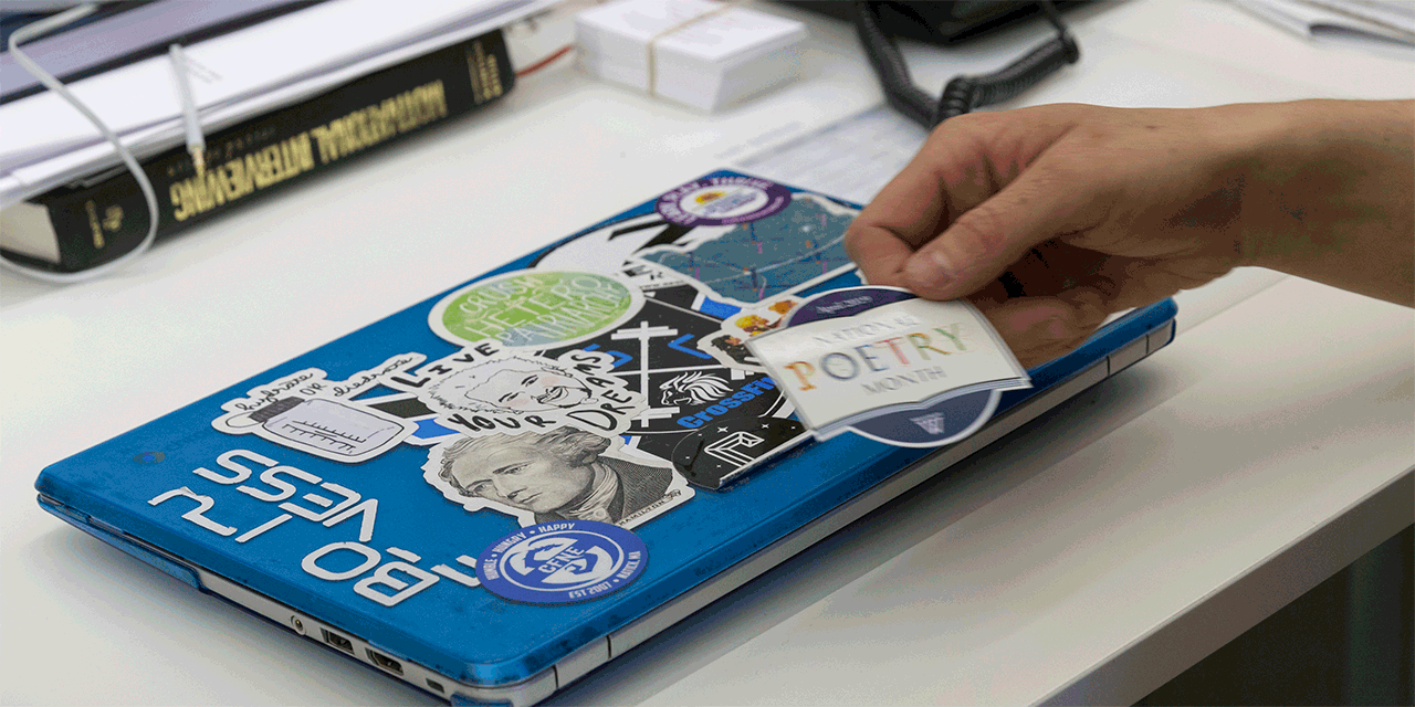 A sticker that reads National Poetry Month is placed on a laptop