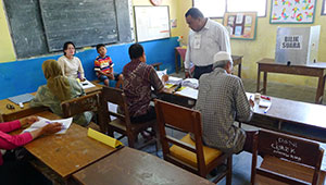 poll workers inside Indonesian schoolroom/polling place