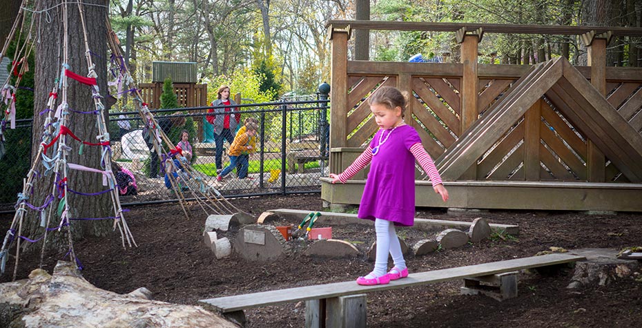 4 year-old girl in purple dress walks a balance beam at Child Study Center playground