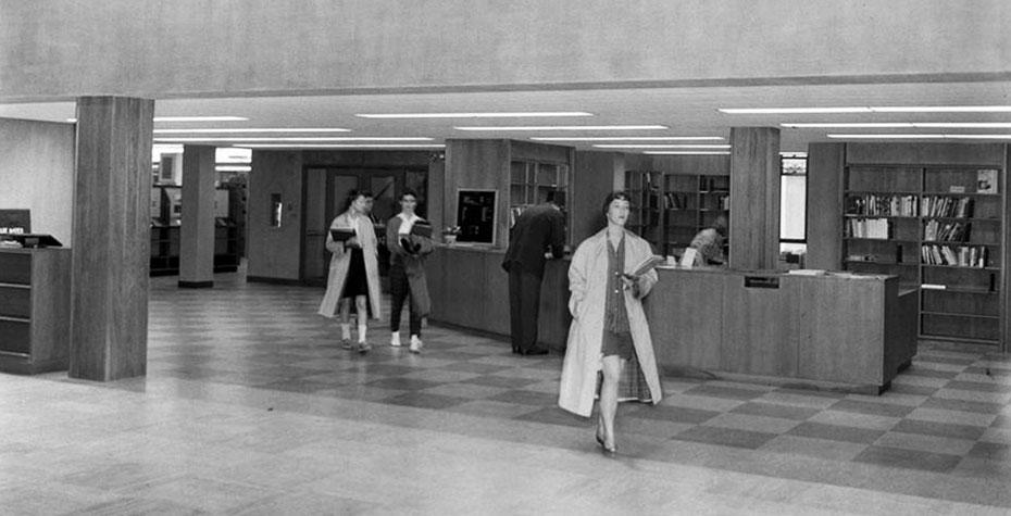 1959 photo: 3 students head out of library, wearing coats and bobby socks