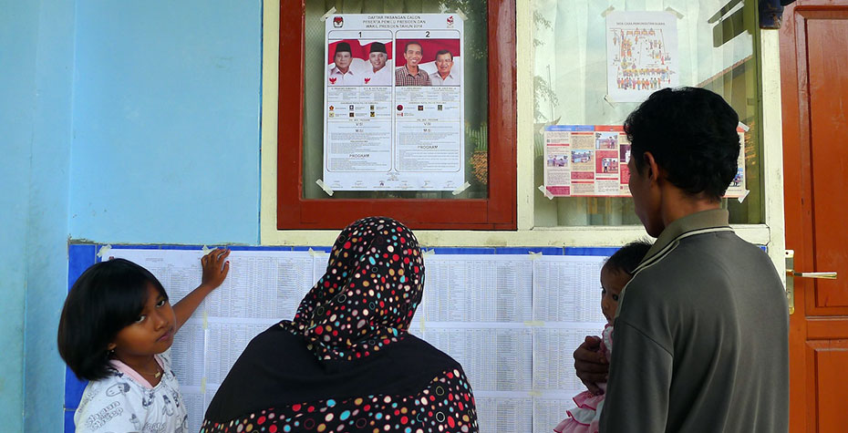 family reads poster at Indonesia polling place