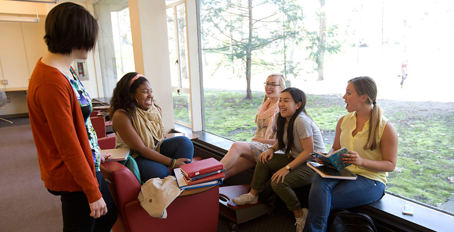 diverse group of students chatting in library by windows
