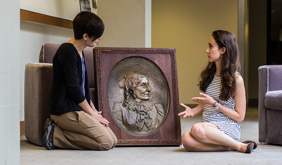 College Archivist Jane Callahan and Student Kathryn Cooperman discuss a bronze relief that was recently located in the College Archives after a months-long search.