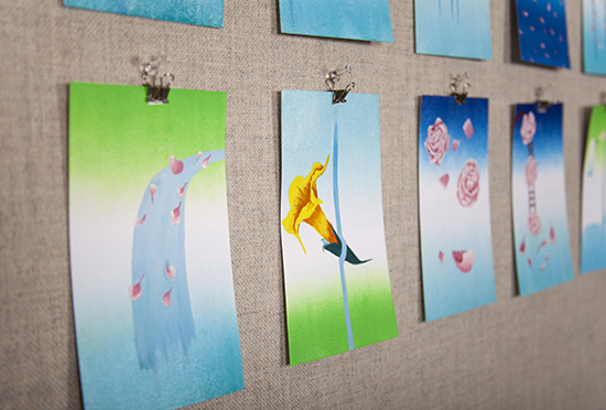 line of small paintings viewed from a side angle, closest painting has green/white/blue gradient background with waterfall and pink petals in front