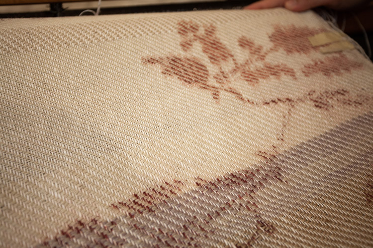 close up on a cream woven textile with red patterns