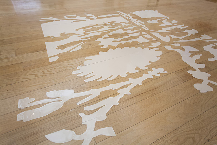 tilted view of a wood floor with a warped floral pattern in light tan or cream vinyl on it