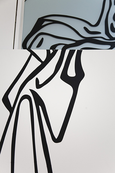 thick black vinyl lines going over the top of a white wall, above and behind on frosted light blue window