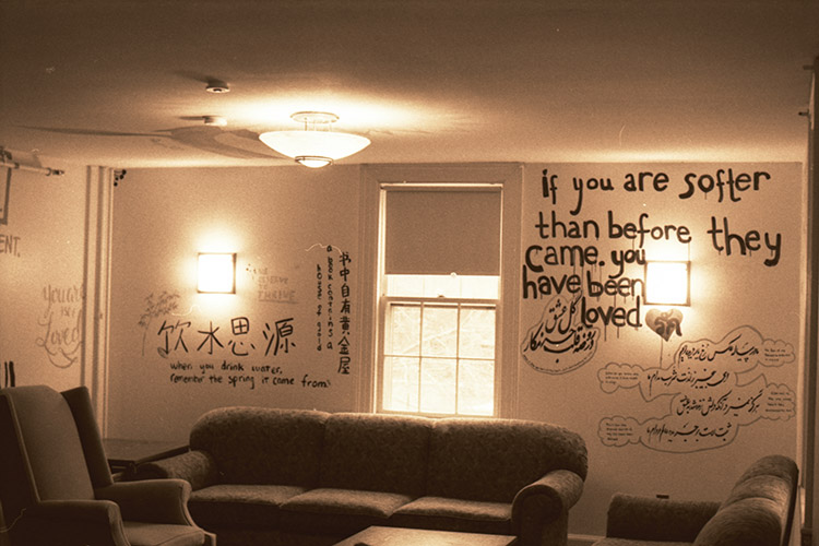 warm-toned photograph of a room with text in multiple languages painted on the walls