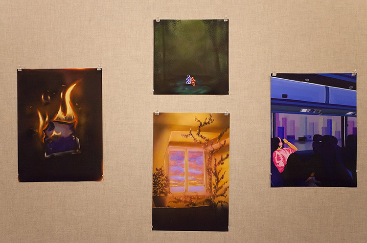 four digital paintings hung on a fabric wall: a hole in burning paper, a green forest scene with two glowing figures, a sunset window seen from inside, and a person watching a cityscape through the window of a subway