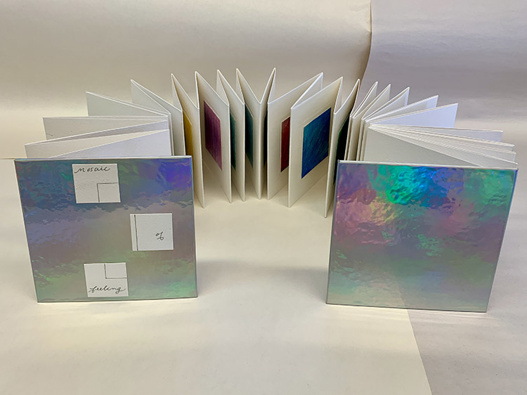 accordion book open in a U shape to show colors in the pages with rainbow paper on the covers at the ends