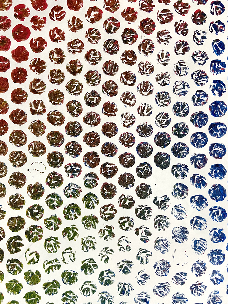 a print of bubblewrap, grading from red ink at top left to blue at bottom right