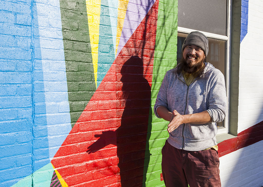 Professor Dave Olsen poses with his Allston mural