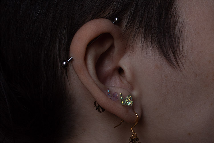 close up color photograph of an ear with several piercings