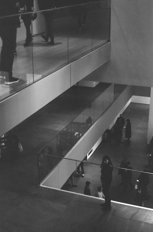 multiple vertical levels of glass-walled museum walkways with patrons