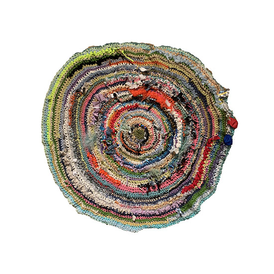 top down view of a colorful handwoven round rug made of many different materials