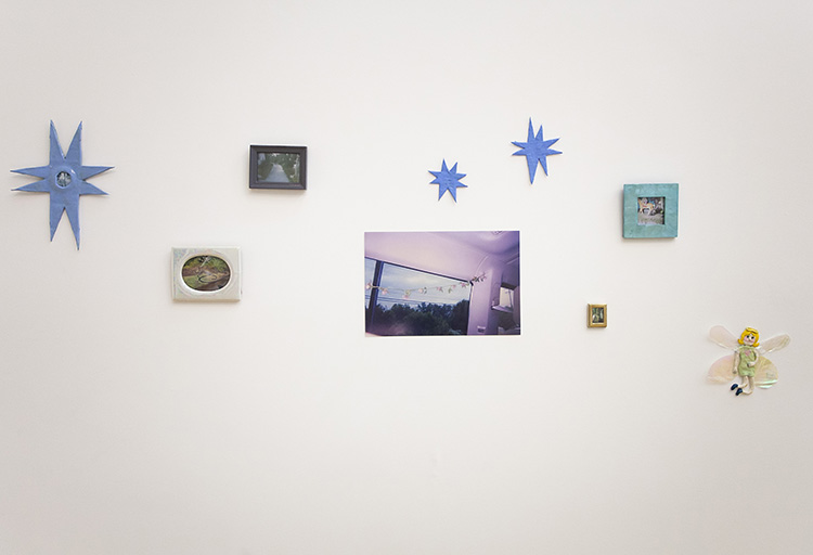 white gallery wall hung salon style with small photos, 8 pointed blue stars, and a fairy