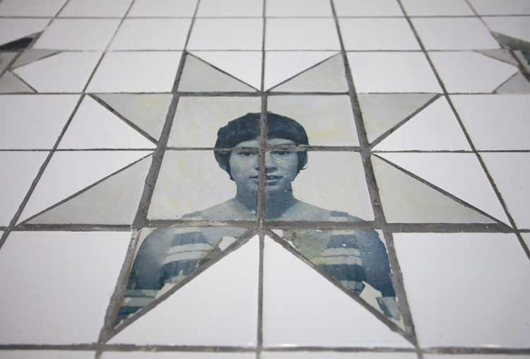 angled view of white tiles inset with an 8 pointed star printed with a blue-toned portrait of a woman with short dark hair