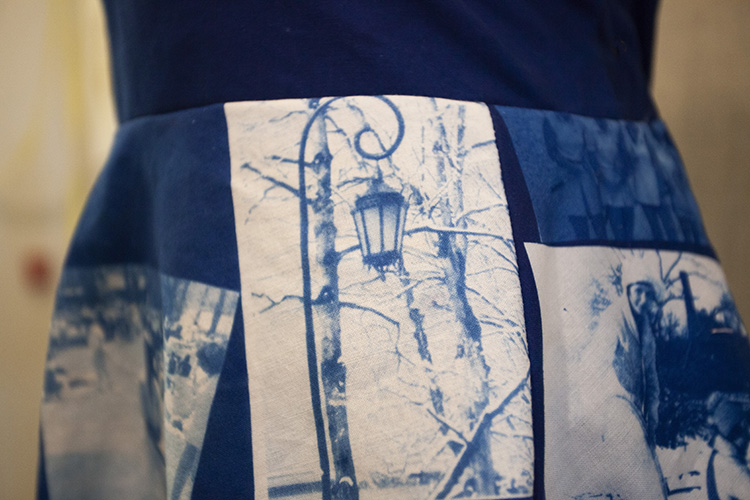 close up on waist of dress printed with cyanotypes, showing blue and white image of the classic Wellesley College lamp in front of bare trees