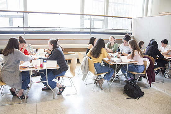 3 tables of students participate in a quilting workshop in the Sculpture Court