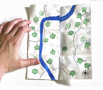 printed map with hand at left holding it open