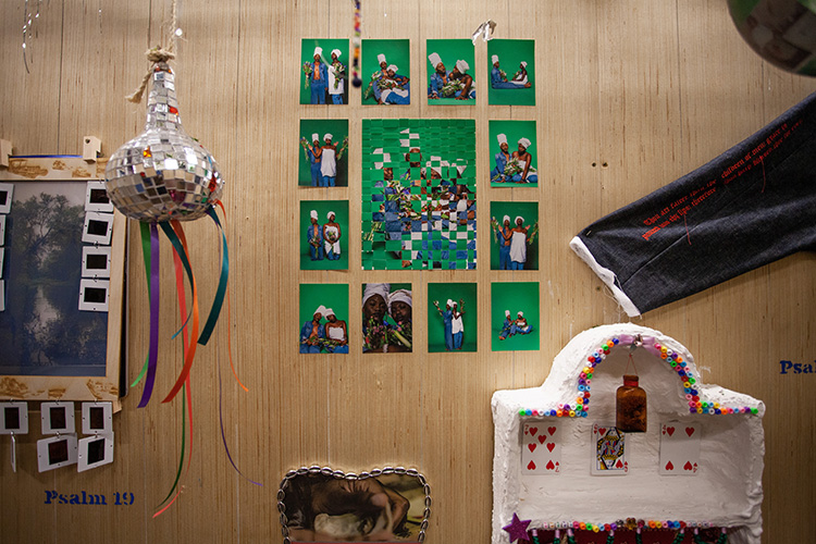 wood walled installation with hanging disco gourd, photo collage, embroidered jacket sleeve, and more