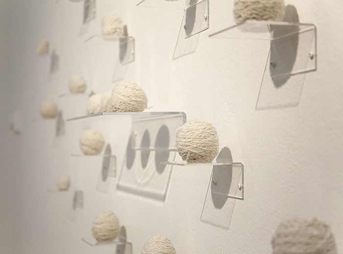 balls of white yarn on clear shelves, viewed from an angle
