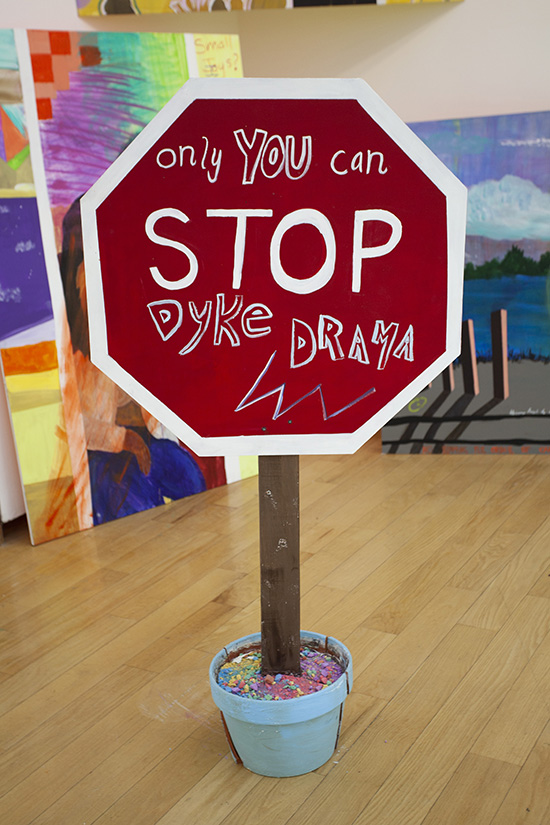 a handpainted stop sign with its base in a light blue flower pot; the sign reads 'only YOU can STOP DYKE DRAMA'