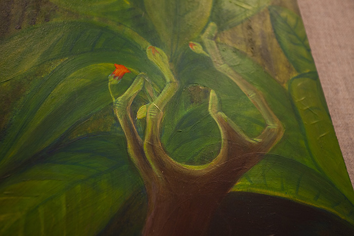 close-up on a painting showing a brown-skinned hand transforming into green plant branches with red flower buds