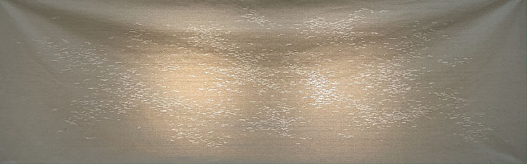 a tan canvas lit from behind with many small lines cut through it