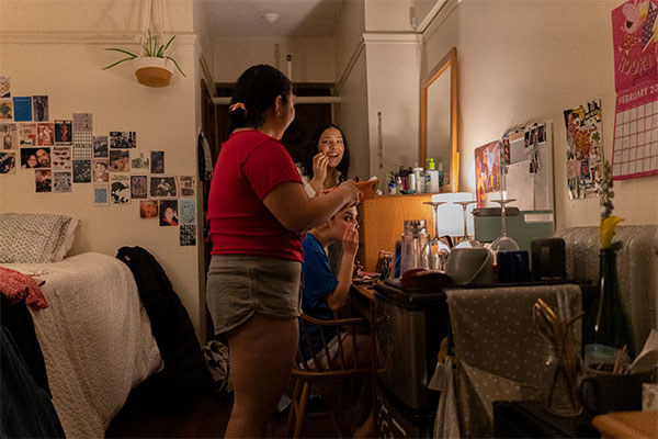 three people in a dorm room, getting ready for a night out