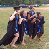 Four seniors flex muscles, wearing academic robes over rowing suits