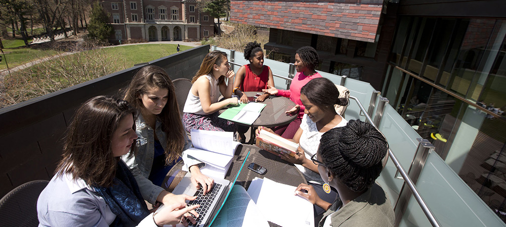 Students gather around tables outside to study 