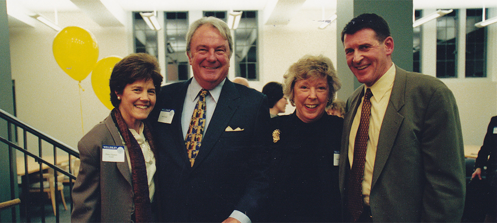 Betsy and two men and one woman dressed in suits and smiling