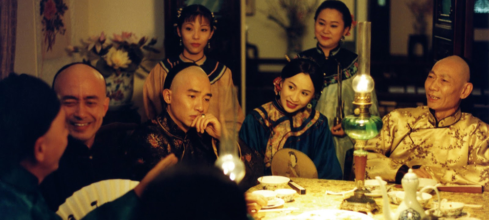 A still from the film Flowers of Shanghai, Around a table at a party, all guests appear to be smiling except one man