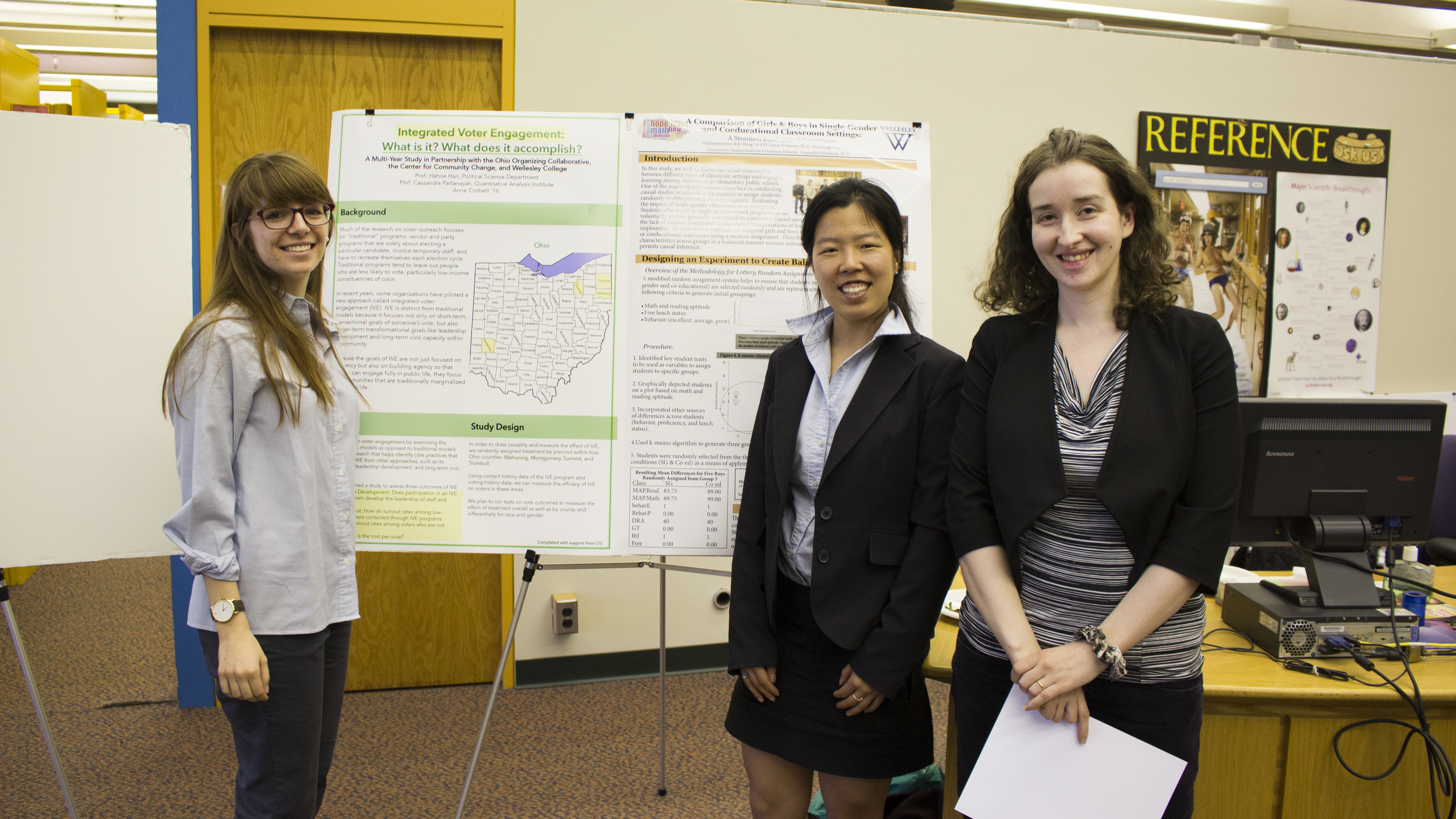 Three students standing in front of their research presentation display