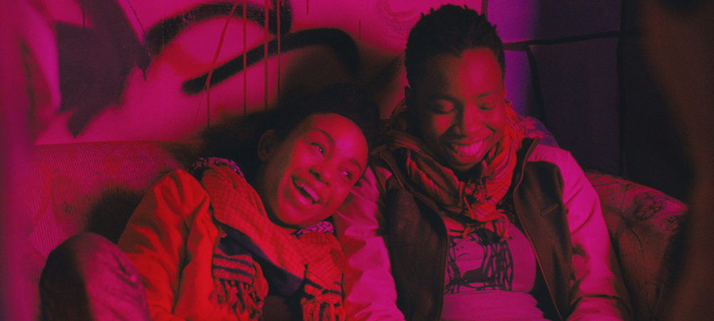 a still from the film Pariah, two women are sitting next to each other on a couch, laughing