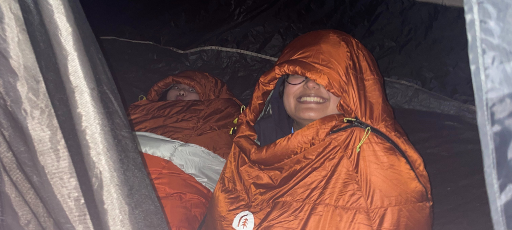 Students smiling in sleeping bags
