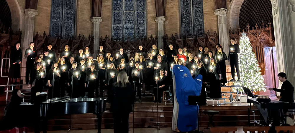 A choir singing by candlelight in Houghton Chapel.
