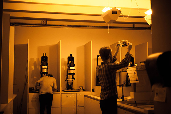 photographers working in the darkroom with yellow light