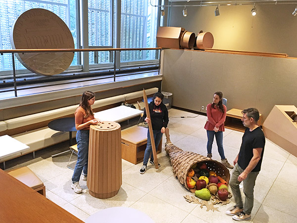 students and faculty install large cardboard sculptures in the Sculpture Court