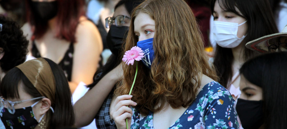 A students holds a flower to their face to smell.