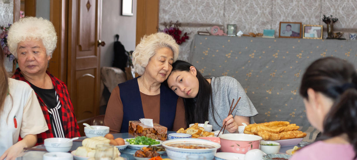 Still from the film The Farewell by Lulu Wang, a young Asian American woman rests her head on her grandma, an older Chinese woma
