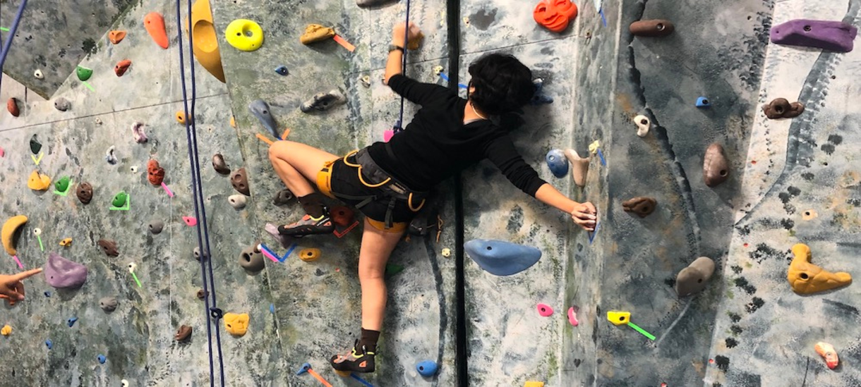 A student climbing on the climbing wall